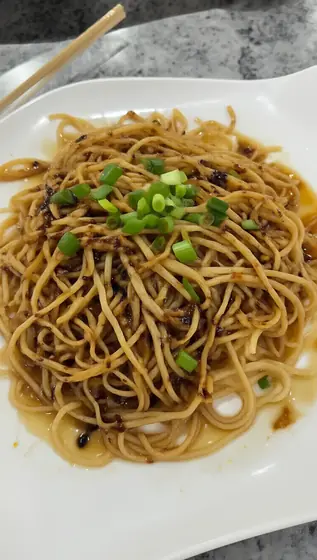dry noodles coat with soy sauces and garnish some green onion. Chinese dishwear, mouth-watering, enticing, chopstick